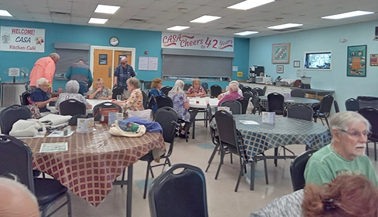 Group of seniors playing card games at various tables at CASA