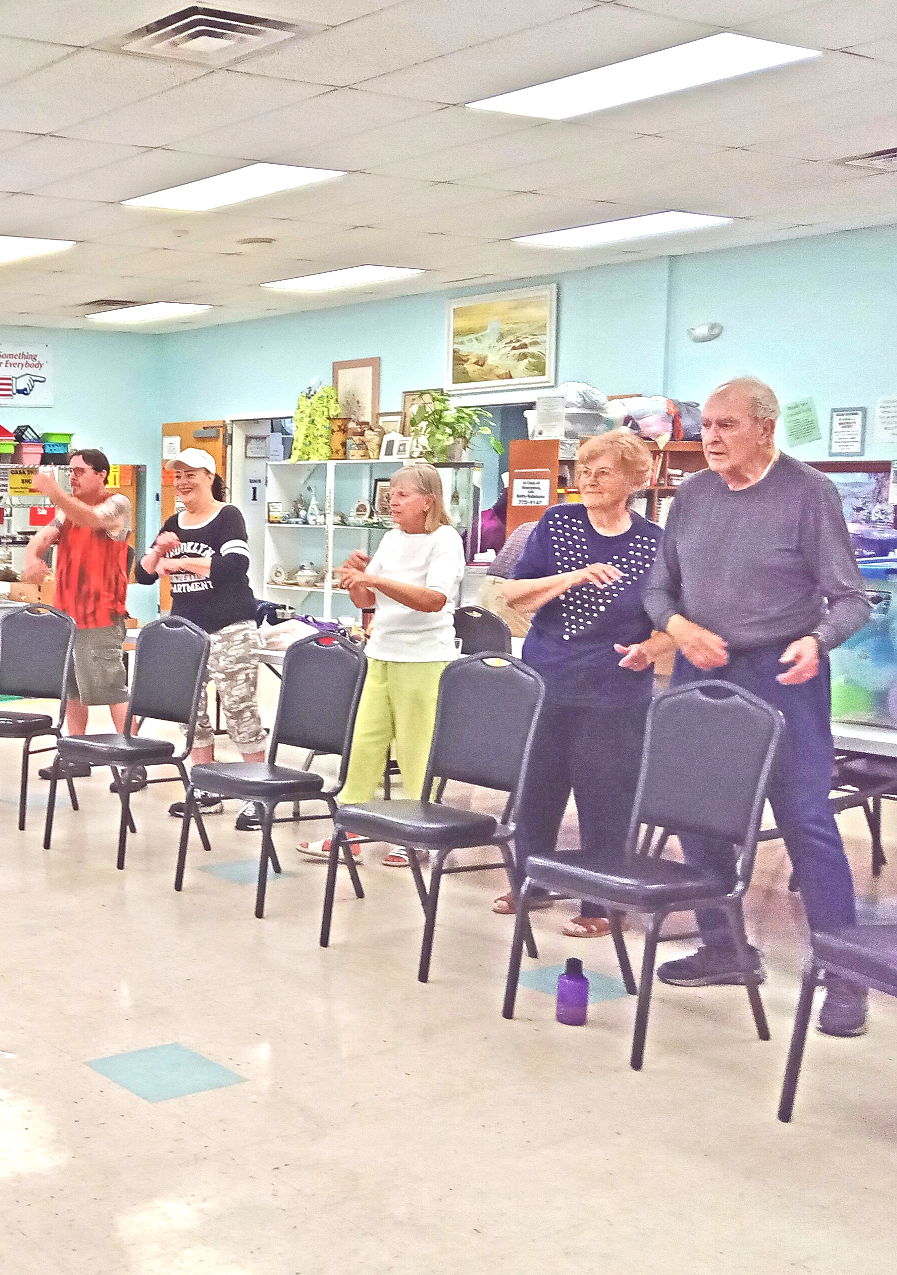 group of seniors in a line behind chairs doing exercises in a group